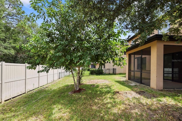 view of yard featuring a sunroom and a fenced backyard