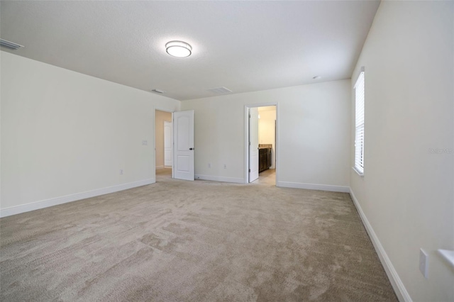 spare room with light carpet, visible vents, and baseboards