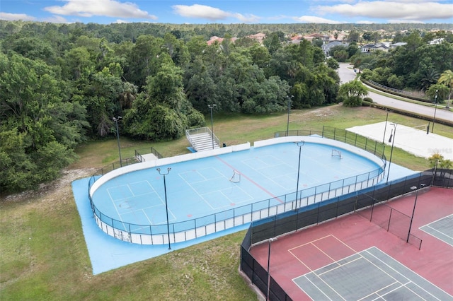 pool with a forest view, a tennis court, and fence