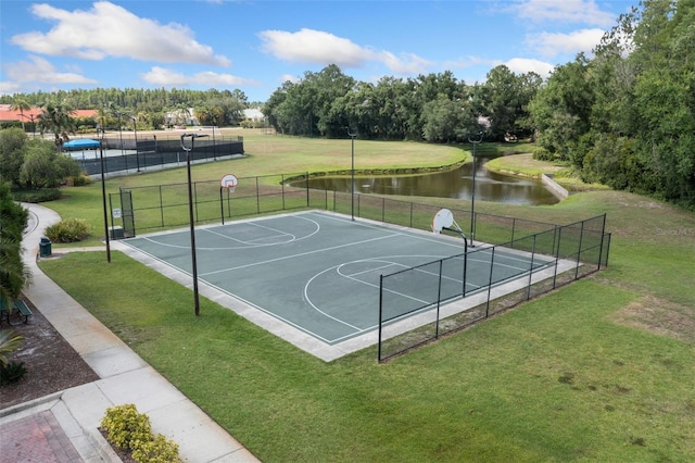 view of sport court with a water view, community basketball court, fence, and a yard