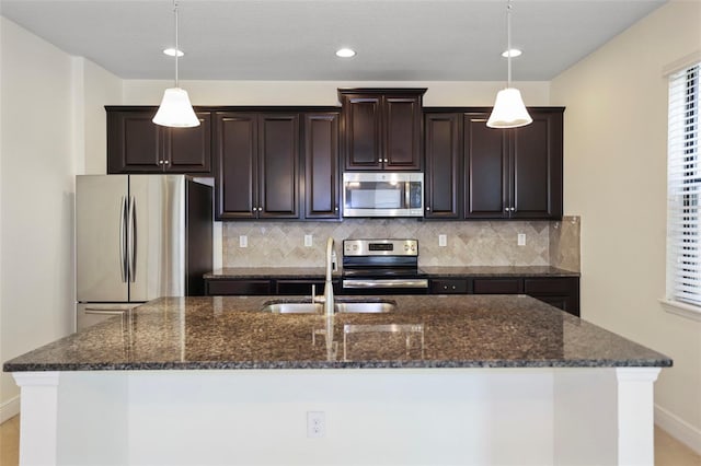 kitchen featuring an island with sink, tasteful backsplash, stainless steel appliances, and a sink