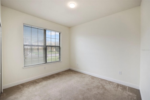 carpeted spare room featuring baseboards