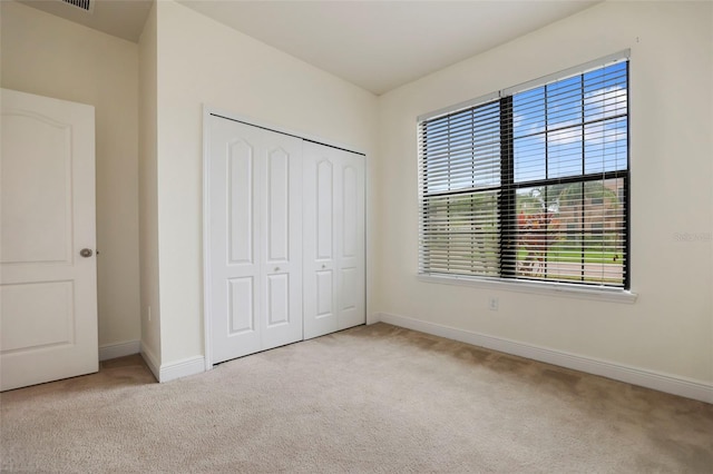 unfurnished bedroom featuring carpet floors, a closet, and baseboards