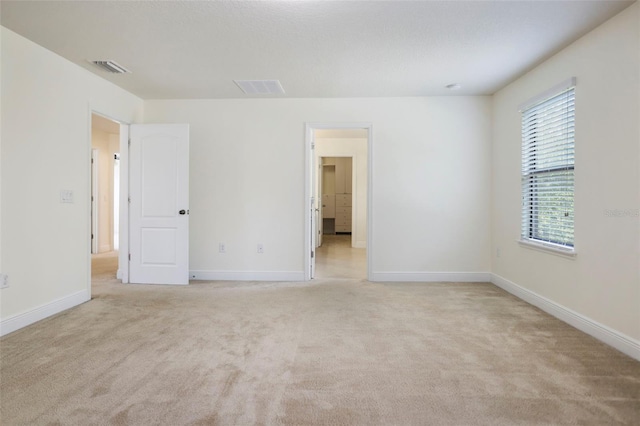 unfurnished room featuring light colored carpet, visible vents, and baseboards