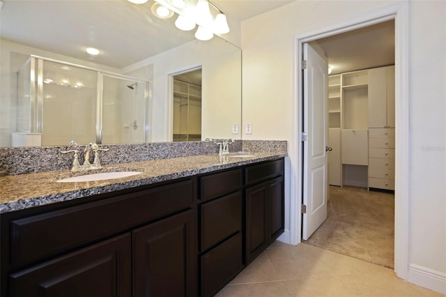 full bathroom featuring a walk in closet, double vanity, a sink, a shower stall, and tile patterned floors