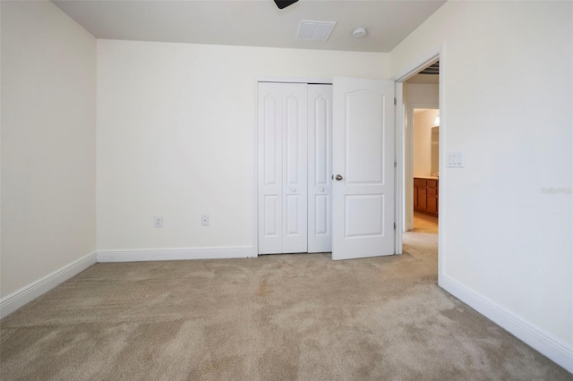 unfurnished bedroom with visible vents, baseboards, a closet, and light colored carpet