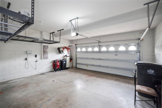 garage with concrete block wall, electric panel, and a garage door opener