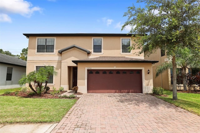 traditional home featuring a garage, a front lawn, decorative driveway, and stucco siding