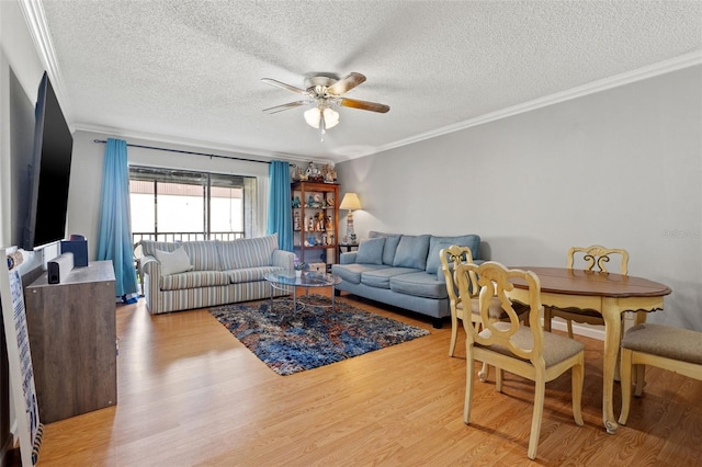 living room with a textured ceiling, ceiling fan, ornamental molding, and light wood-type flooring