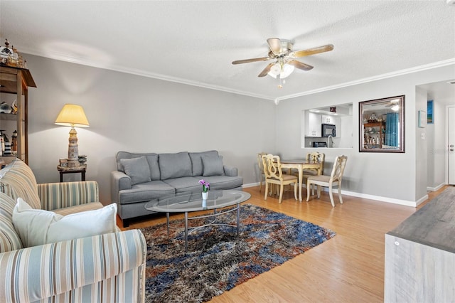 living room with ceiling fan, a textured ceiling, light hardwood / wood-style flooring, and ornamental molding