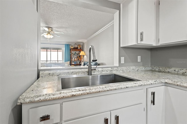 kitchen featuring sink, crown molding, a textured ceiling, white cabinets, and ceiling fan