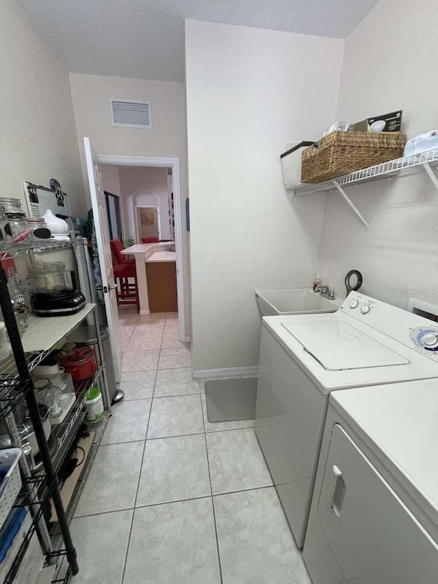 laundry room with light tile patterned floors, independent washer and dryer, and sink