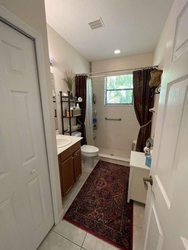 bathroom with a textured ceiling, vanity, a shower with curtain, toilet, and tile patterned floors