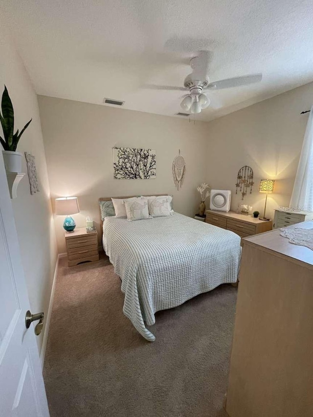 bedroom featuring a textured ceiling, ceiling fan, and dark colored carpet