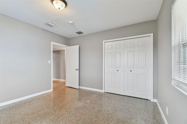 unfurnished bedroom with multiple windows, a closet, and a textured ceiling