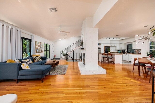 living room featuring ceiling fan, light hardwood / wood-style floors, and vaulted ceiling