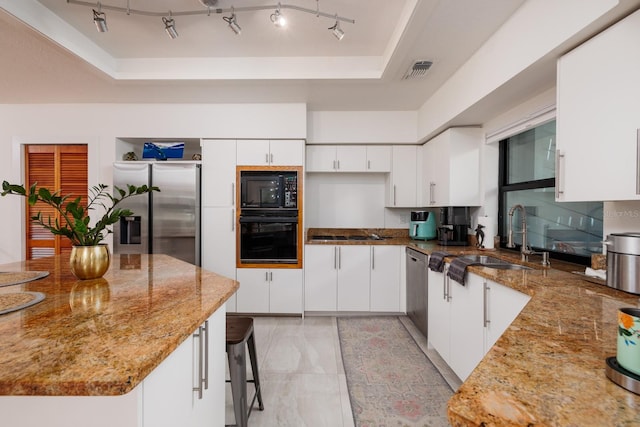 kitchen featuring white cabinetry, sink, a raised ceiling, light stone counters, and black appliances