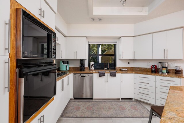 kitchen with black appliances, a raised ceiling, white cabinets, and light tile patterned flooring