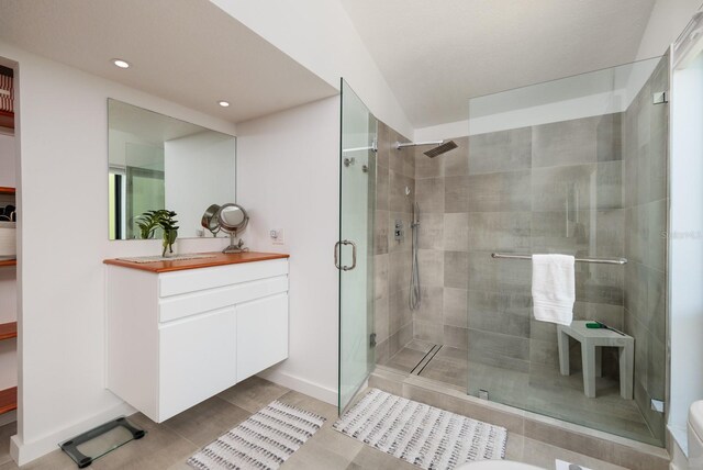 bathroom with a shower with door, vanity, and tile patterned flooring