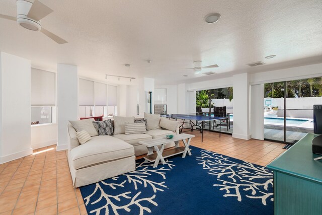 tiled living room featuring ceiling fan, rail lighting, and a textured ceiling