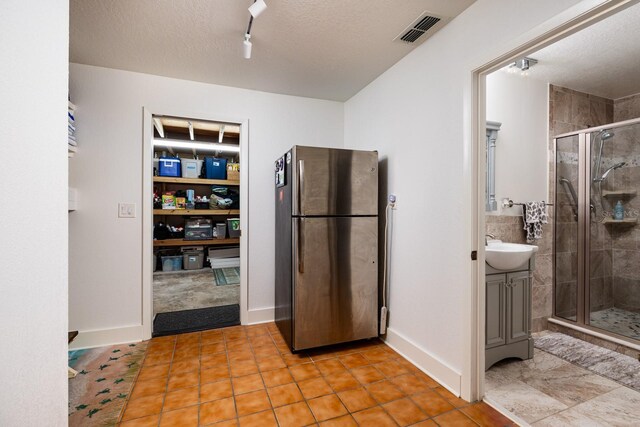 bathroom featuring tile patterned floors, vanity, a shower with shower door, and a textured ceiling