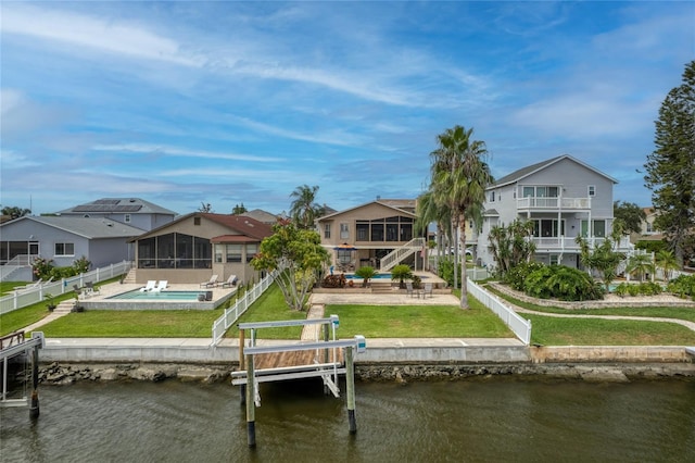 rear view of property featuring a water view, a lawn, and a fenced backyard