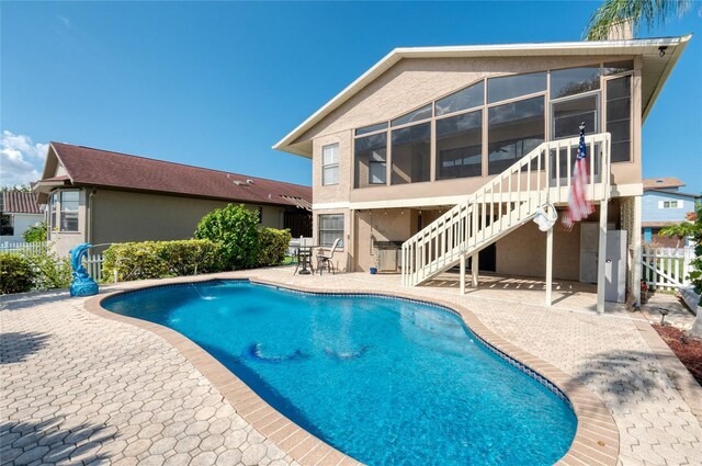 view of swimming pool featuring a patio area and a sunroom