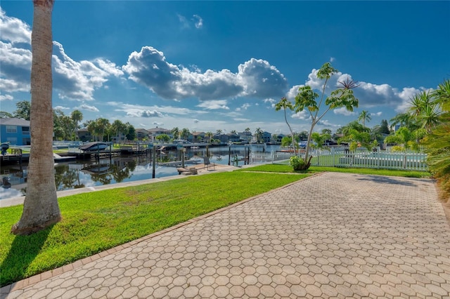 view of community with a water view, a boat dock, fence, and a yard