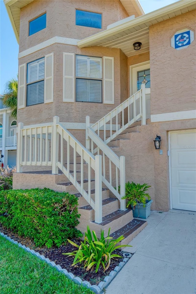 property entrance with a garage and stucco siding