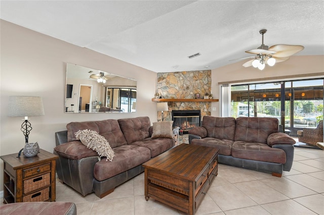 living area with light tile patterned floors, visible vents, a textured ceiling, and a stone fireplace