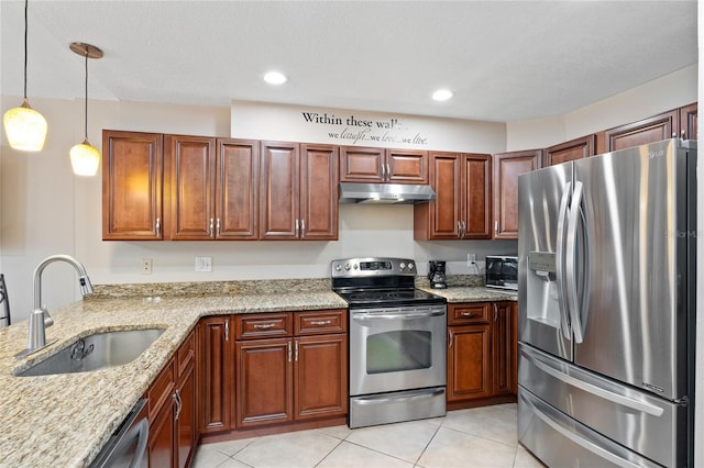 kitchen featuring under cabinet range hood, stainless steel appliances, a sink, light stone countertops, and decorative light fixtures