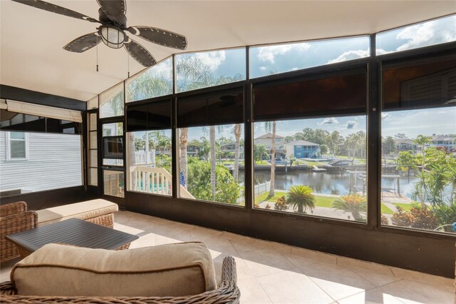 sunroom featuring ceiling fan and a water view