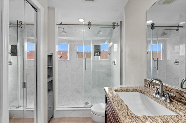 bathroom with toilet, tile patterned flooring, a marble finish shower, and vanity