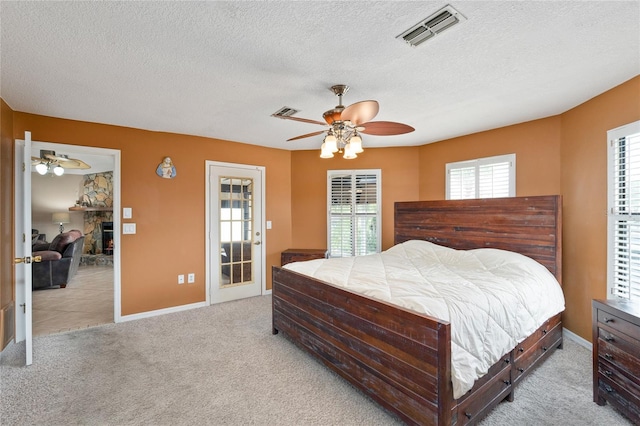 bedroom with carpet floors, visible vents, a fireplace, and a textured ceiling