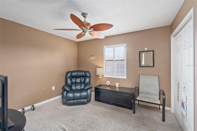 living area with ceiling fan, a textured ceiling, baseboards, and carpet flooring