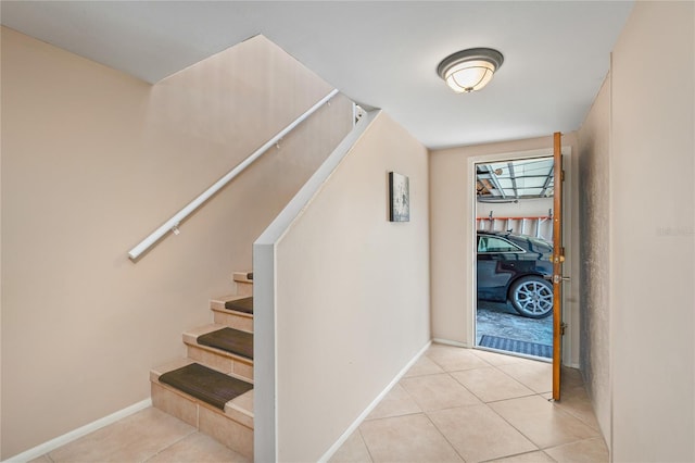 stairway with baseboards and tile patterned floors