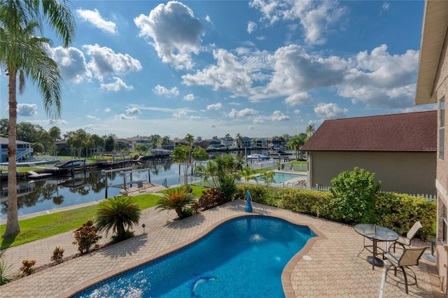 pool with a patio area, a boat dock, boat lift, and a water view