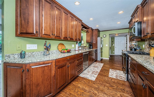 kitchen featuring light stone counters, stainless steel appliances, dark hardwood / wood-style flooring, sink, and ornamental molding