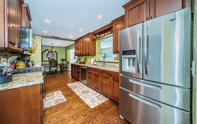 kitchen with decorative light fixtures, light stone counters, sink, dark wood-type flooring, and appliances with stainless steel finishes