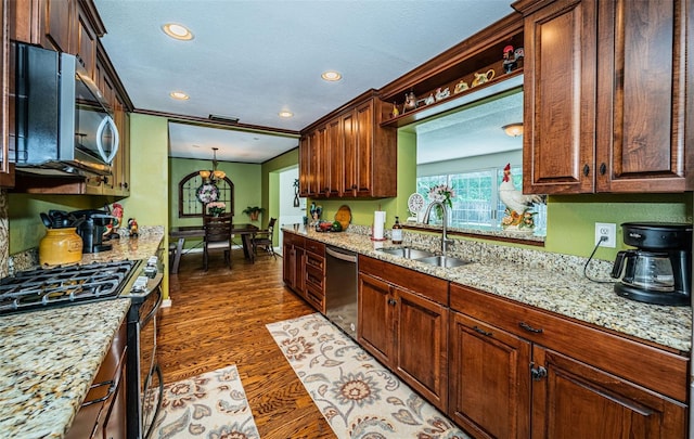 kitchen with pendant lighting, dark hardwood / wood-style flooring, light stone counters, sink, and appliances with stainless steel finishes