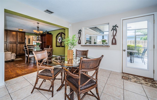 dining area with a textured ceiling, an inviting chandelier, and light tile patterned floors