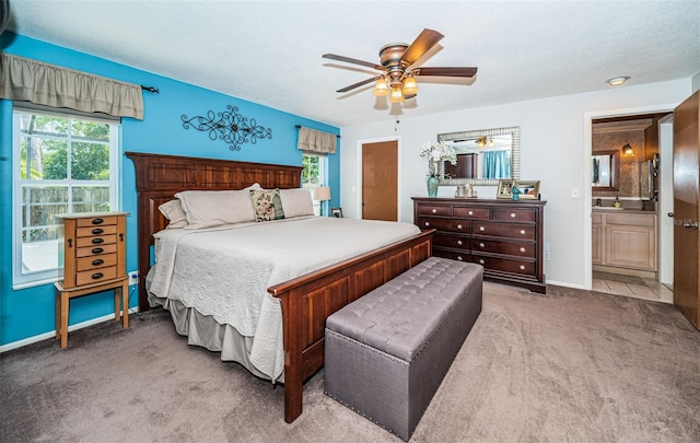 bedroom featuring ceiling fan, light colored carpet, connected bathroom, and a textured ceiling