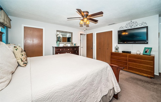 carpeted bedroom with two closets, ceiling fan, and a textured ceiling