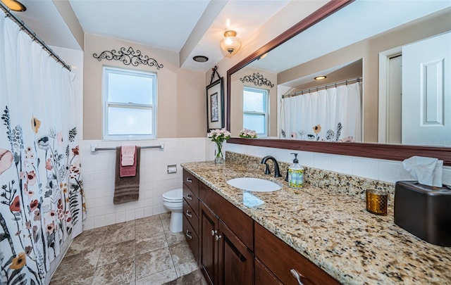 bathroom with vanity, toilet, and tile walls