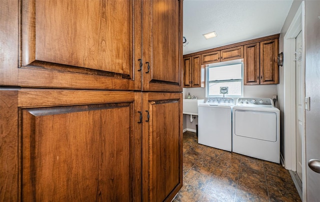 clothes washing area with a textured ceiling, cabinets, and washing machine and dryer