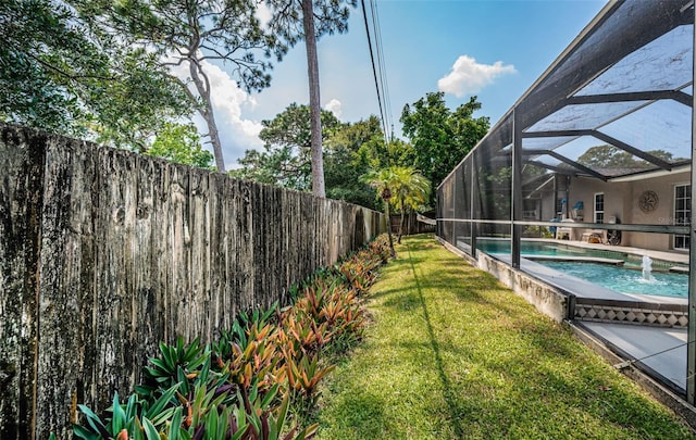 view of yard with glass enclosure, pool water feature, and a fenced in pool