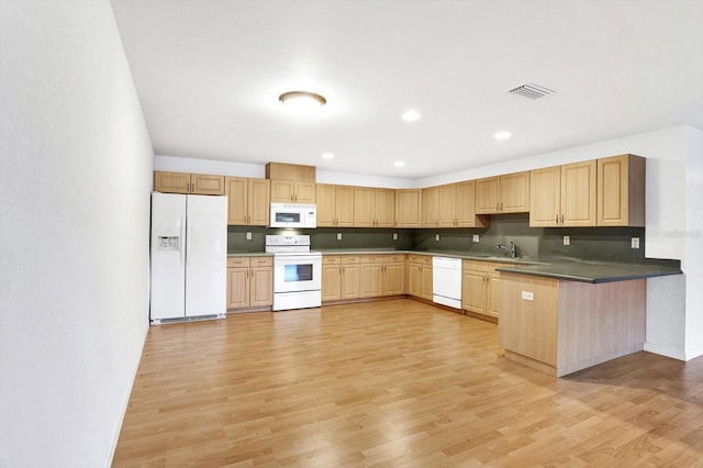 kitchen with kitchen peninsula, light wood-type flooring, sink, and white appliances