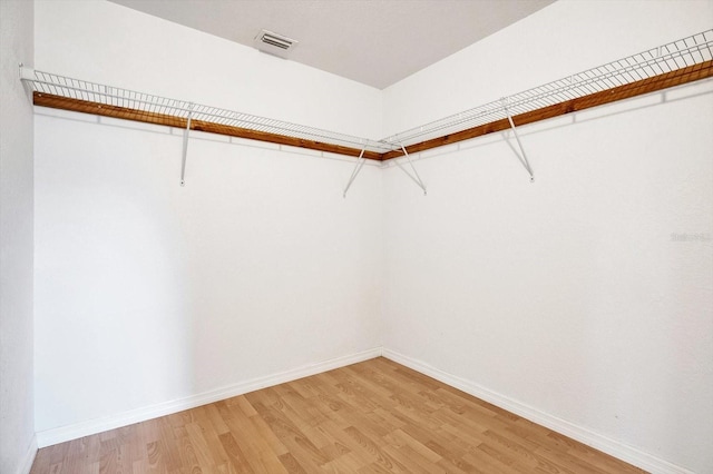 walk in closet with light hardwood / wood-style floors