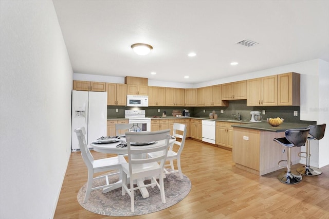 kitchen featuring white appliances, light hardwood / wood-style floors, kitchen peninsula, sink, and decorative backsplash