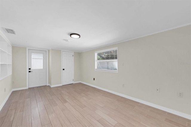 spare room featuring light hardwood / wood-style flooring and crown molding